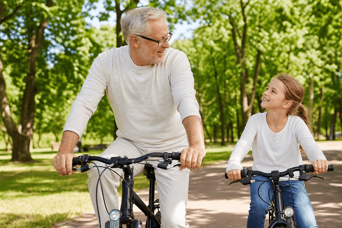 Großvater und Enkelin auf dem Fahrrad im Park — Flexibilität über Generationen